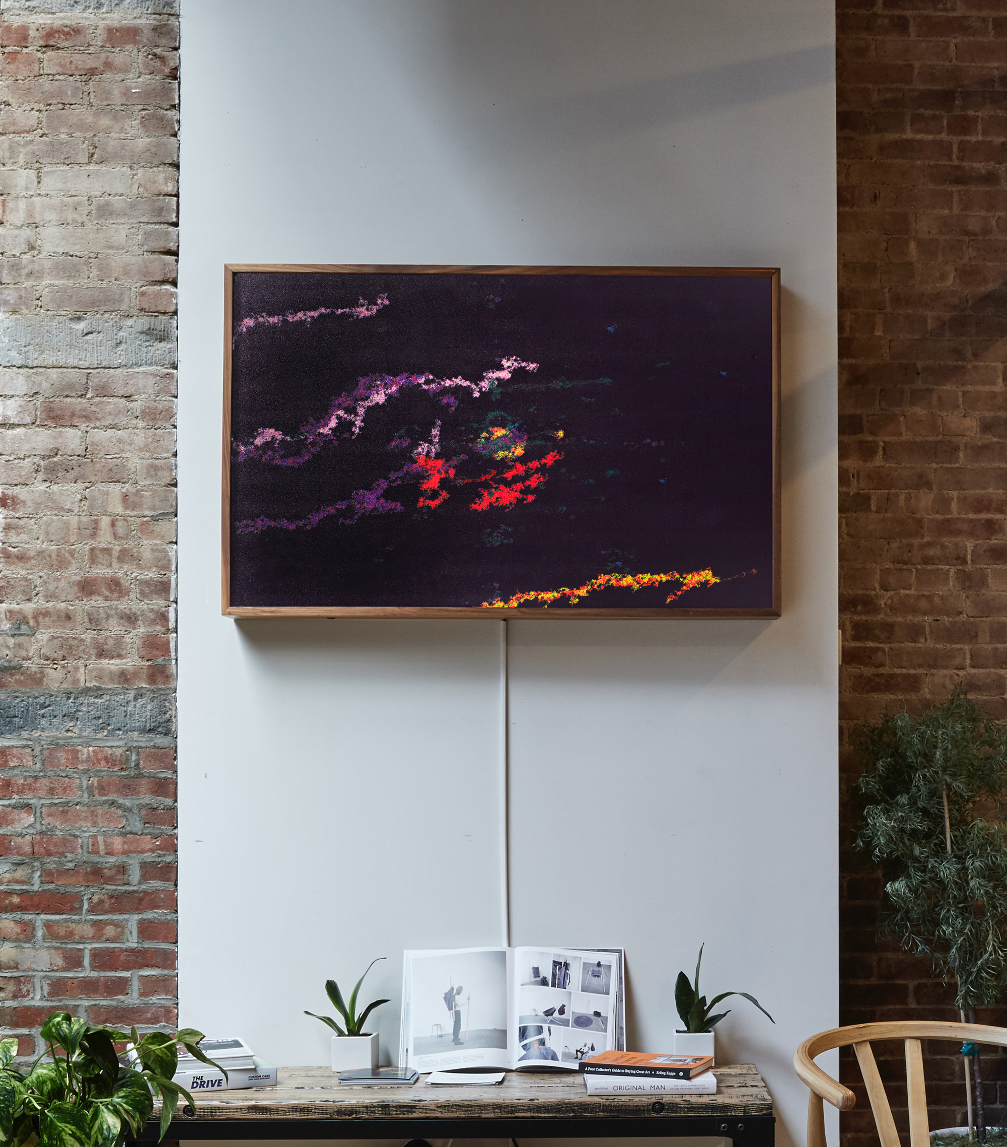Photograph showing a large artwork in a wooden frame hanging above a coffee shop looking space