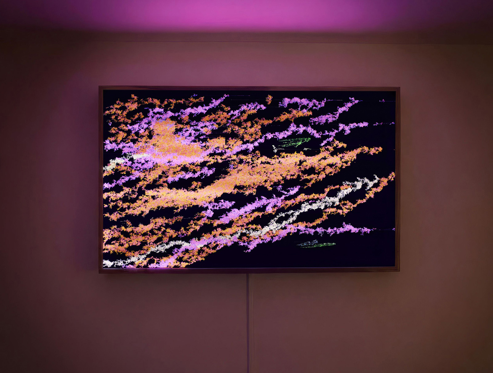 Photograph showing a large, illuminated artwork consisting of orange, pink, and white striated digital forms in a wooden frame, emitting a strong pinkish glow over the entire room